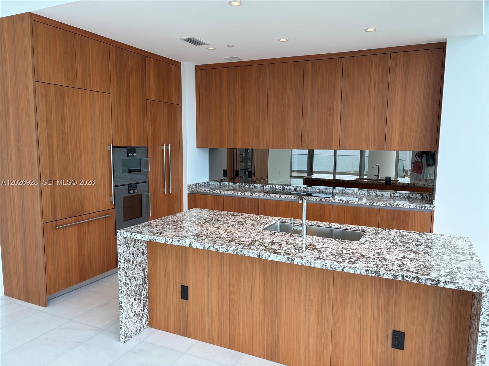 175 Southeast 25th Road, Unit 901 Miami, FL 33129 - Photo 5 of 18 a kitchen with kitchen island granite countertop wooden cabinets and a refrigerator