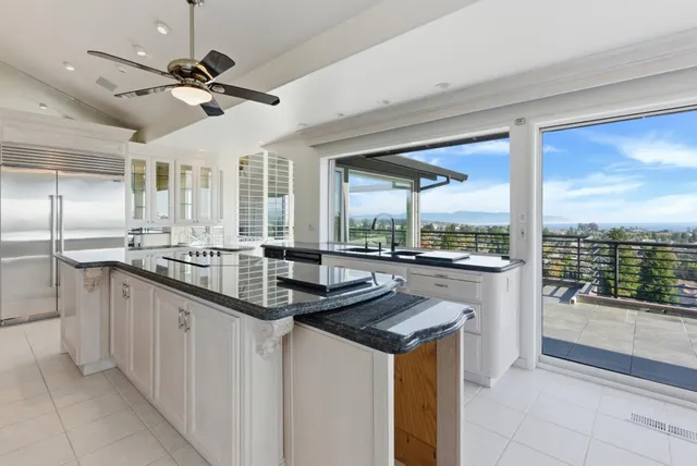 a large white kitchen with a large window and stainless steel appliances