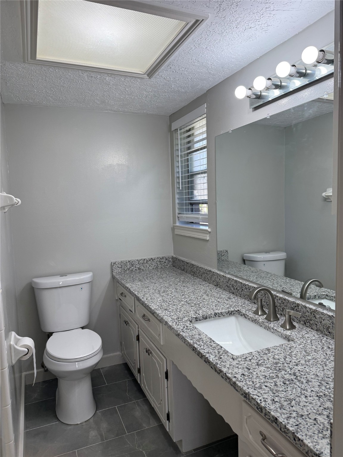 5622 Killough Street Houston, TX 77086 - Photo 14 of 21 a bathroom with a granite countertop toilet a sink and a mirror