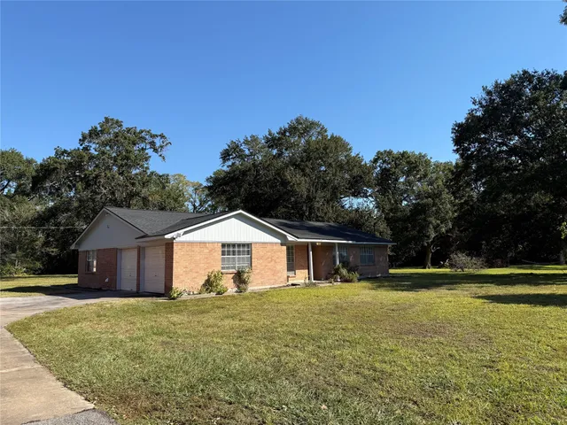 a front view of house with yard and trees in the background
