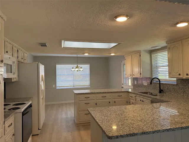 a kitchen with stainless steel appliances granite countertop a sink a stove and a refrigerator