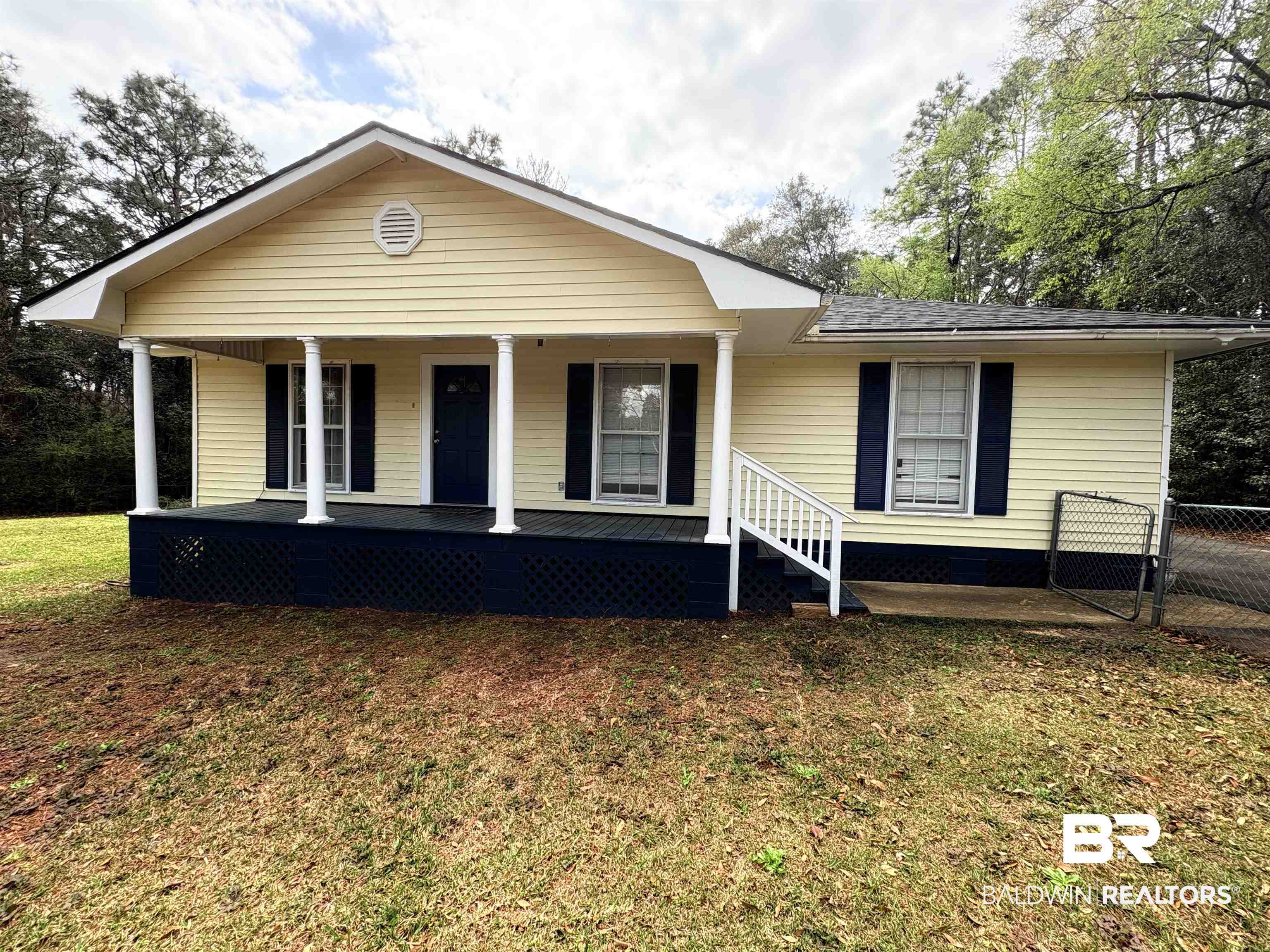 View of front of property featuring a front lawn, fence, and covered porch