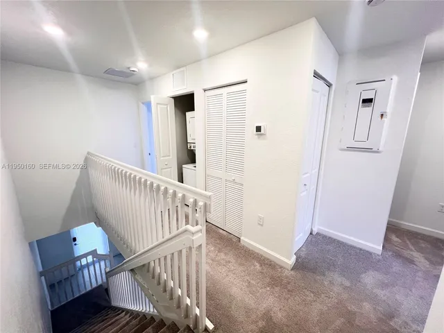 a view of an empty room with wooden floor and stairs