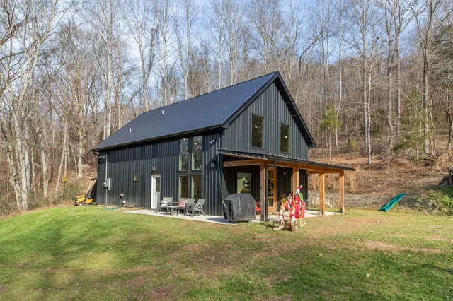 a front view of a house with large trees