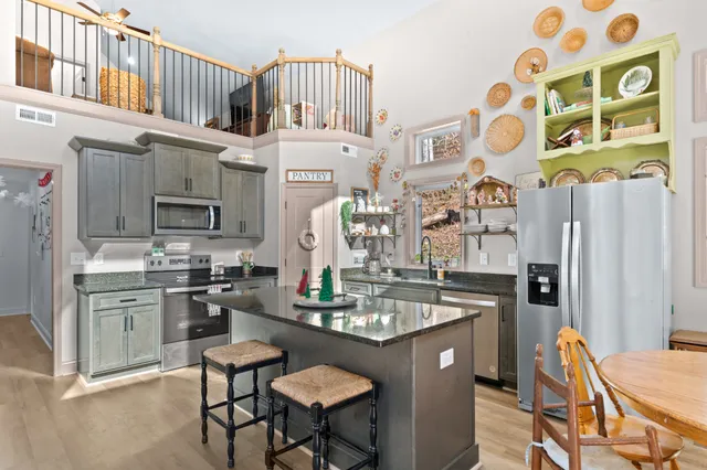 a living room with stainless steel appliances granite countertop a couch and wooden floor
