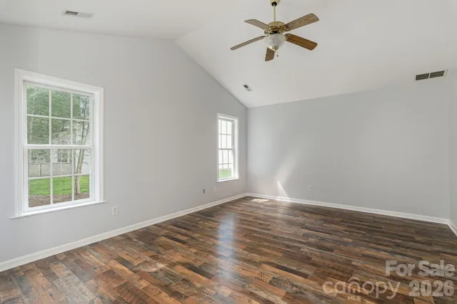 a view of empty room with wooden floor and fan