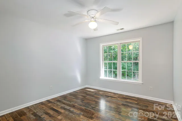 an empty room with a window and a fan