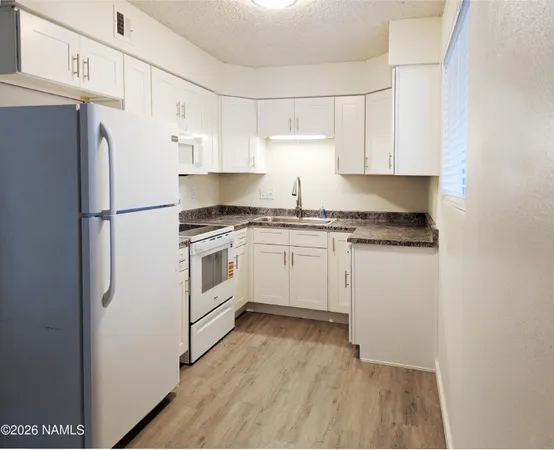 a kitchen with white cabinets and white appliances