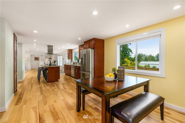 a kitchen with stainless steel appliances wooden floor dining table and chairs