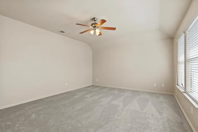 an empty room with windows and a ceiling fan