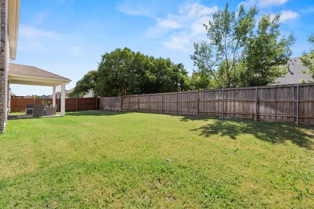 a view of a yard with a large tree and wooden fence