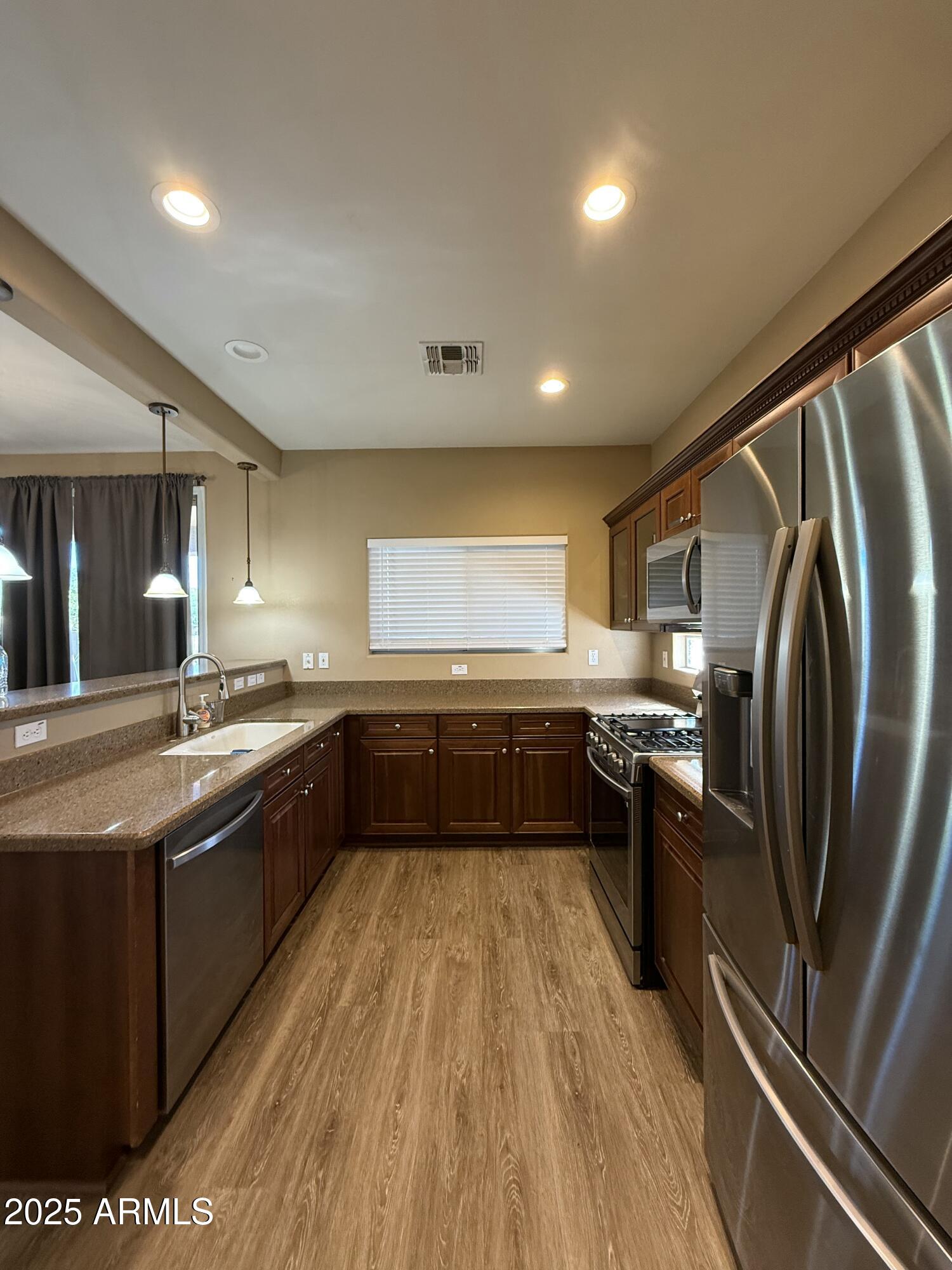 21975 East Vía Del Palo Queen Creek, AZ 85142 - Photo 5 of 19 a large kitchen with stainless steel appliances granite countertop a lot of counter space and wooden floor