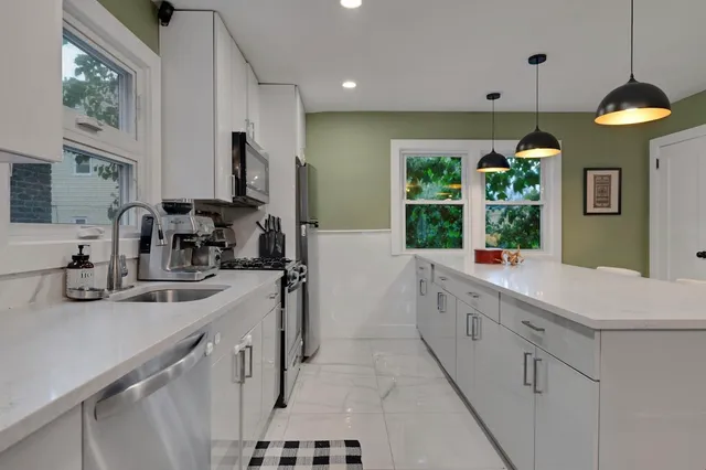 a kitchen with white cabinets and window