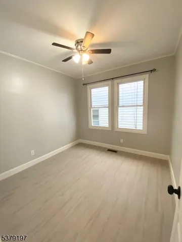 an empty room with chandelier fan and windows