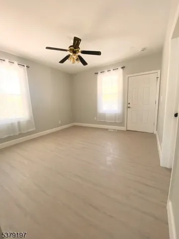an empty room with windows and fan