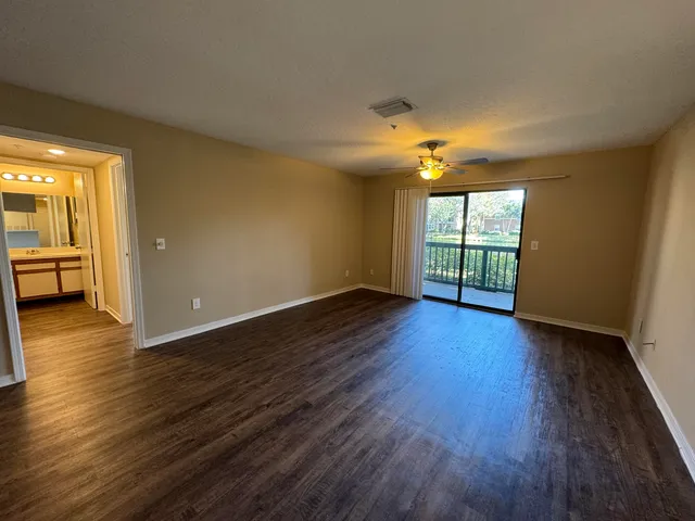 a view of an empty room with a window and wooden floor