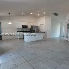 a living room with stainless steel appliances kitchen island granite countertop a sink and cabinets