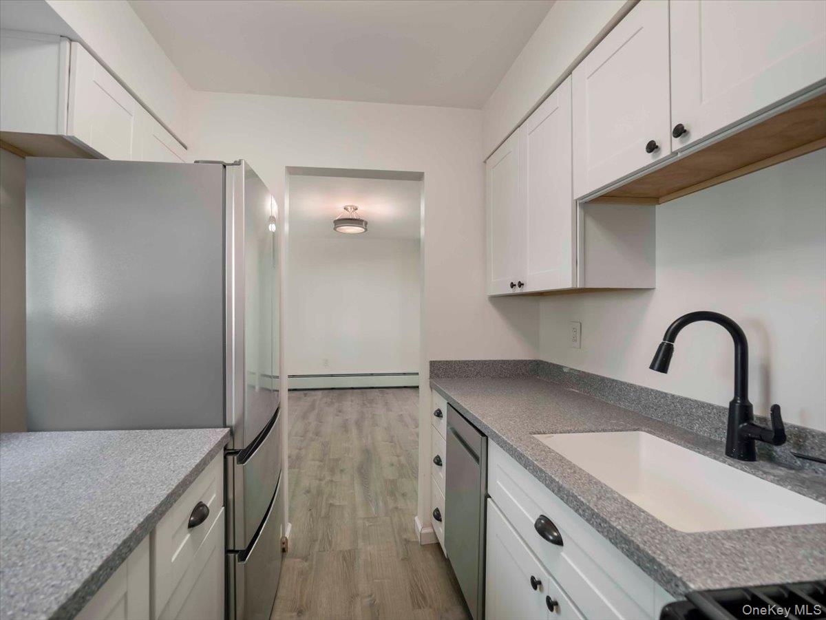 27 Tanager Road, Unit 2702 Monroe, NY 10950 - Photo 3 of 35 Galley kitchen featuring white cabinetry, speckled countertops, stainless steel appliances, a deep single-basin sink, and a matte black gooseneck faucet