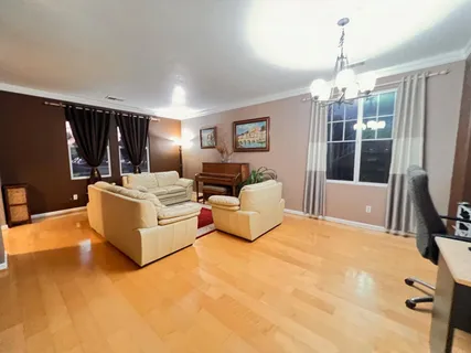 a large bedroom with a bed chandelier dresser and flat screen tv
