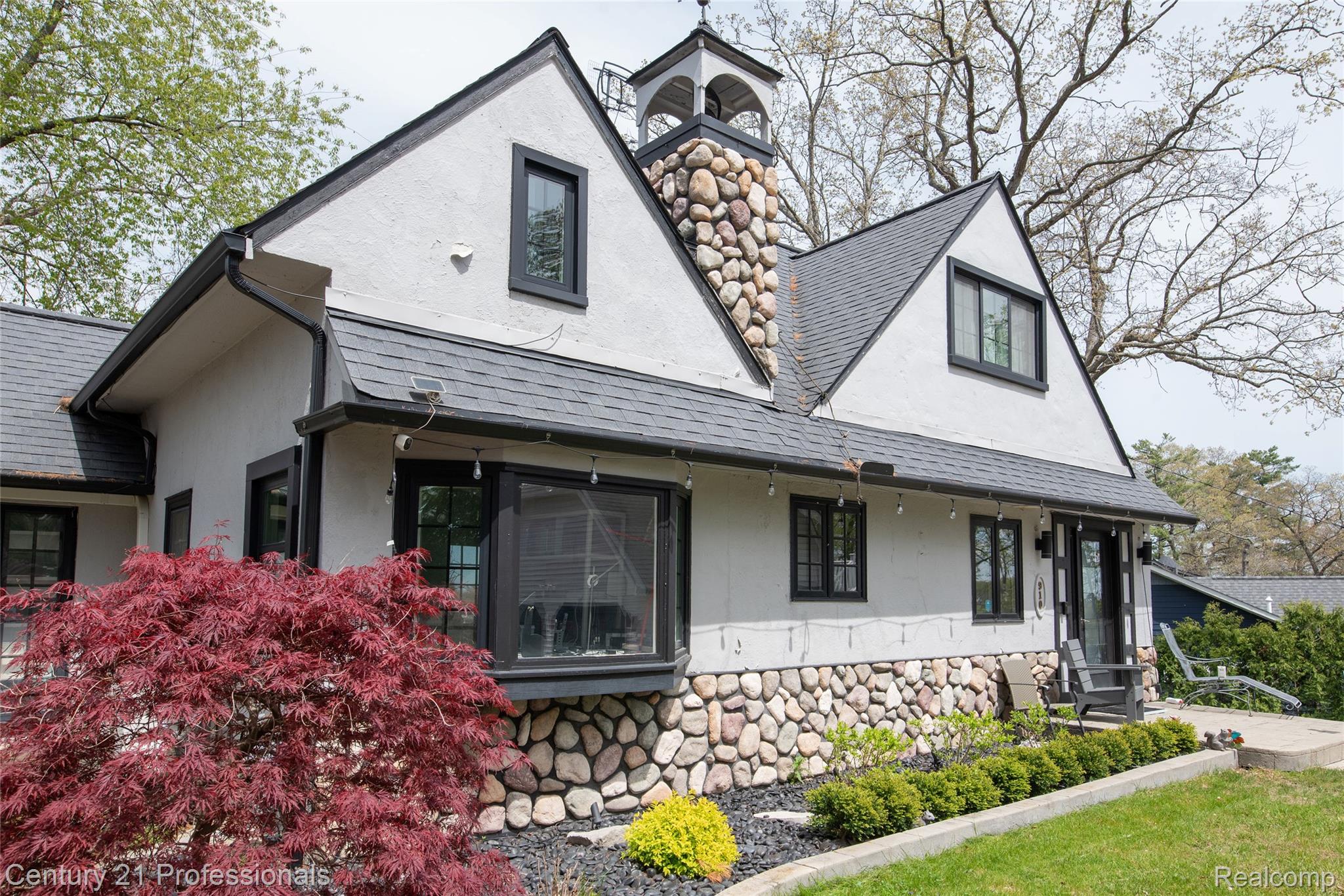 910 West Pine Tree Road West Lake Orion, MI 48362 - Photo 2 of 52 View of front of home featuring roof with shingles, stone siding, stucco siding, a porch, and a chimney