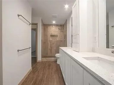 a bathroom with a sink a toilet a mirror and shower