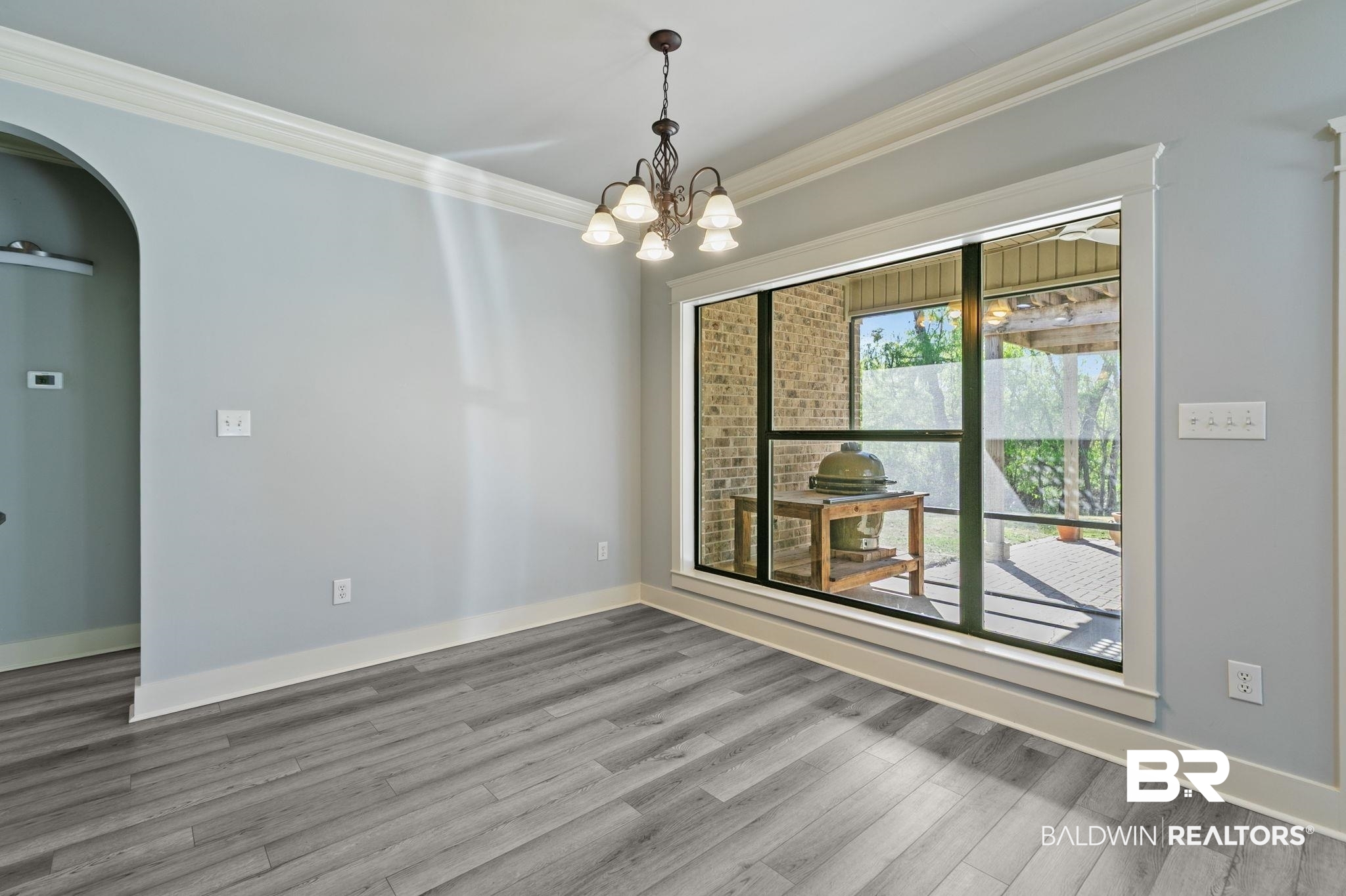 9584 Sanibel Loop Daphne, AL 36526 - Photo 14 of 48 Empty room featuring arched walkways, ornamental molding, hanging lights, and light wood-type flooring