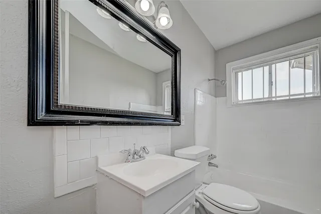 a bathroom with a toilet sink vanity and mirror