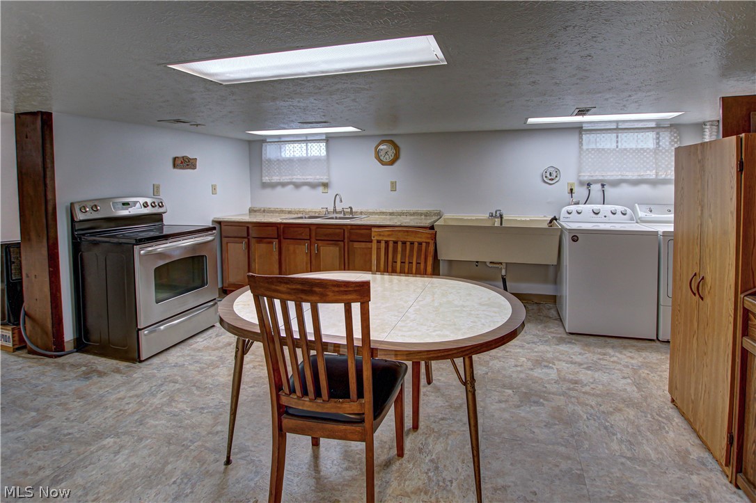 6013 Rousseau Drive Parma, OH 44129 - Photo 33 of 50 Lower level Kitchen featuring sink, stainless steel electric range oven, a textured ceiling, and washing machine and dryer