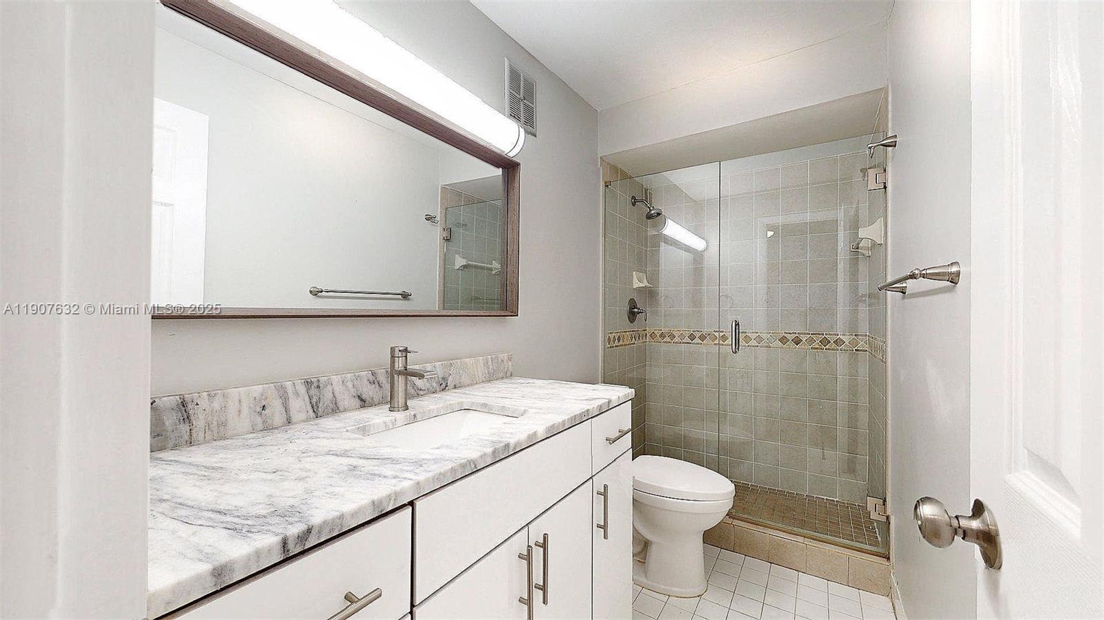 11339 Southwest 71st Street, Unit 11339 Miami, FL 33173 - Photo 25 of 28 a bathroom with a granite countertop sink a toilet and shower