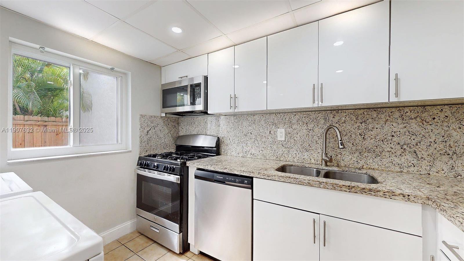 11339 Southwest 71st Street, Unit 11339 Miami, FL 33173 - Photo 27 of 28 a kitchen with stainless steel appliances granite countertop a sink stove and cabinets