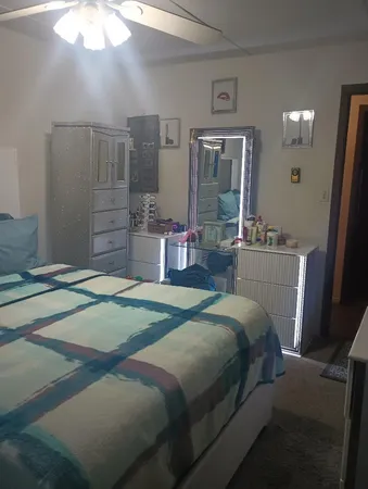 a bedroom with a bed wooden floor and lamp on dresser