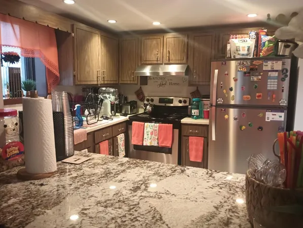 a kitchen with stainless steel appliances kitchen island granite countertop a refrigerator stove top oven and sink