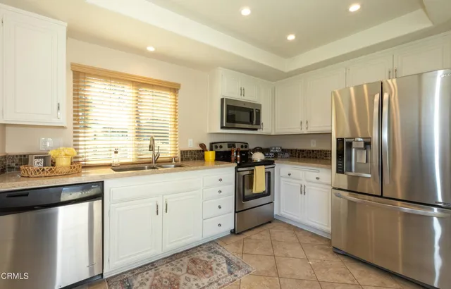 a kitchen with white cabinets stainless steel appliances and a window