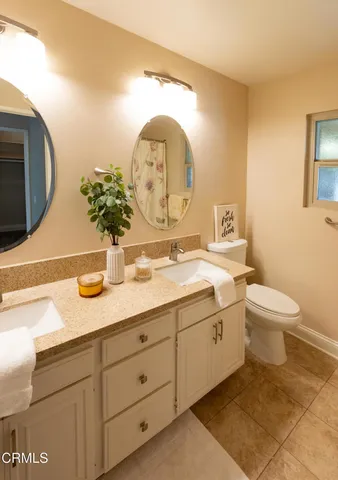 a spacious bathroom with a granite countertop sink a toilet and a mirror