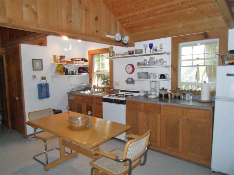 215 Pilgrim Spring Road, Unit 1 Wellfleet, MA 02667 - Photo 4 of 14 a room with stainless steel appliances kitchen island granite countertop a table chairs and a refrigerator