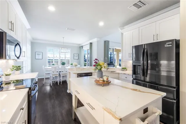 a kitchen with a refrigerator a stove and a dining table with wooden floor