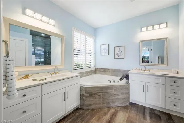 a bathroom with a tub double vanity sink and mirror
