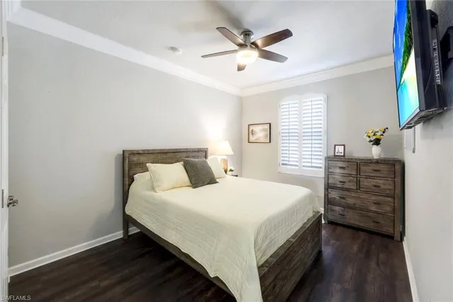 a bedroom with a bed a chandelier and a flat tv screen on dresser