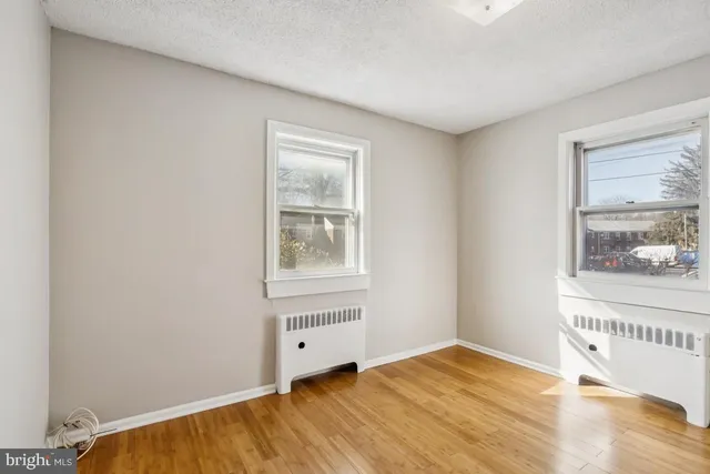a view of an empty room with window and wooden floor