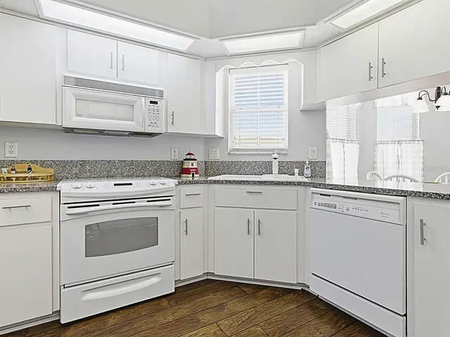 a kitchen with granite countertop white cabinets and white appliances