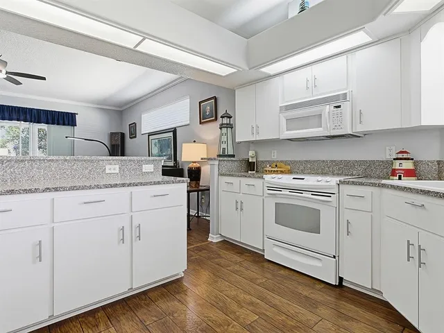 a kitchen with granite countertop white cabinets and white appliances