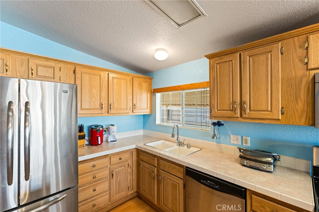 23301 Ridge Rte Drive, Unit 165 Laguna Hills, CA 92653 - Photo 12 of 31 a kitchen with stainless steel appliances granite countertop a sink refrigerator and window