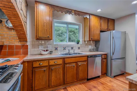 a kitchen with stainless steel appliances granite countertop a refrigerator a sink dishwasher and wooden cabinets with wooden floor