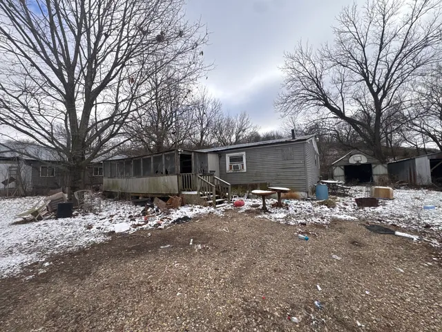 a view of a house with large tree and wooden fence