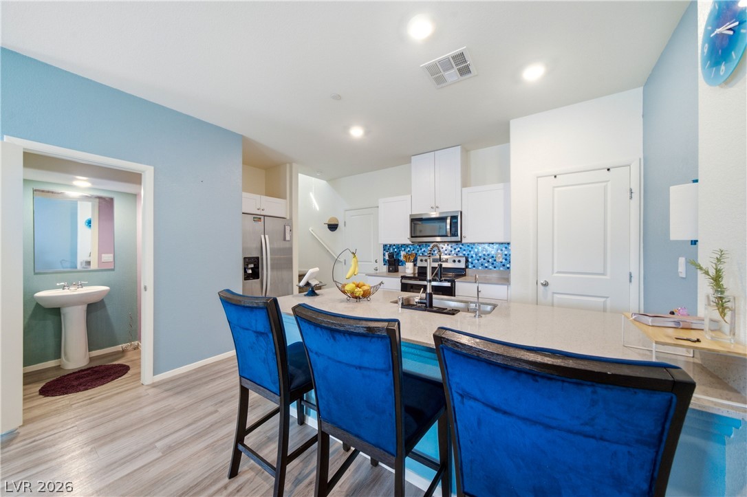 495 Blue Ridge Cove Henderson, NV 89002 - Photo 10 of 32 A vibrant kitchen with a striking blue tiled backsplash and sleek stainless steel appliances offers a delightful culinary space.