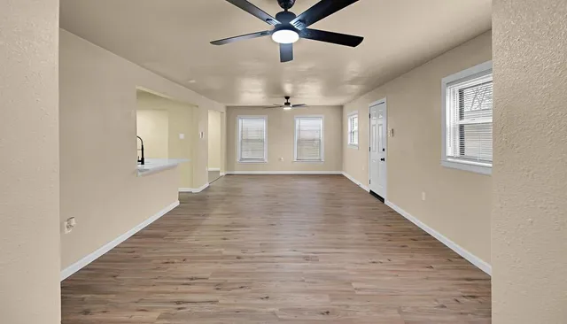 a view of an empty room with wooden floor and a window