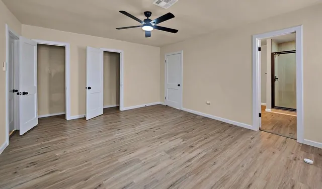 an empty room with wooden floor and ceiling fan