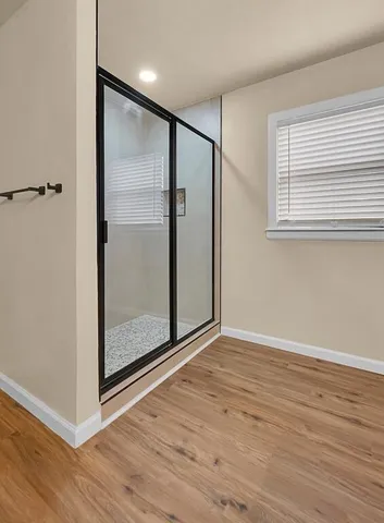 a view of an empty room with wooden floor and a window