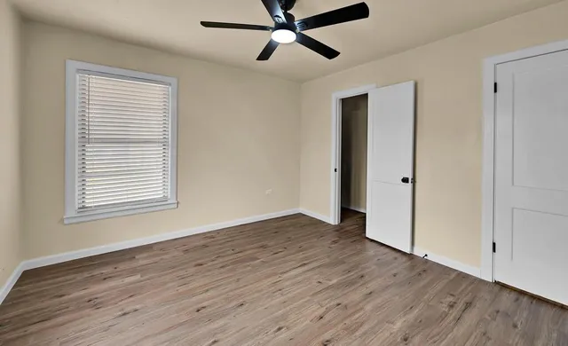 a view of an empty room with wooden floor and a window