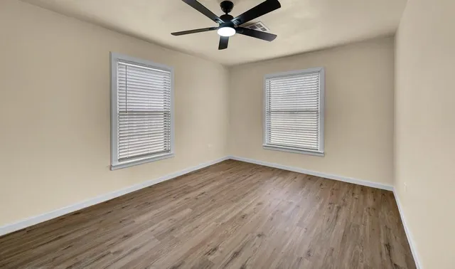 a view of an empty room with wooden floor and a window